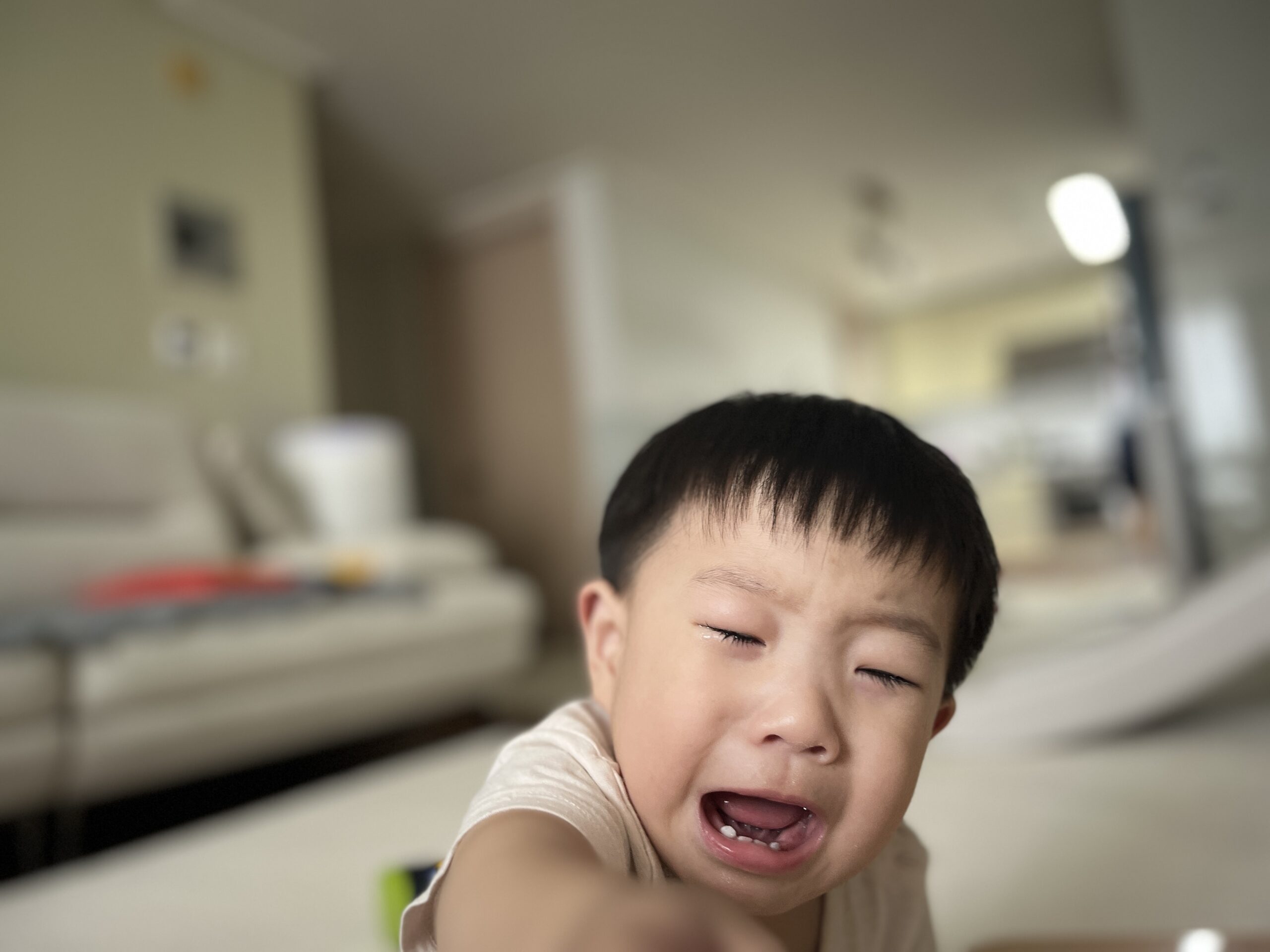 눈을 감고 입을 벌린 채 서럽게 울고 있는 지호의 클로즈업 사진. 볼에는 눈물 자국이 선명하고, 배경은 흐리게 처리되어 있다.
